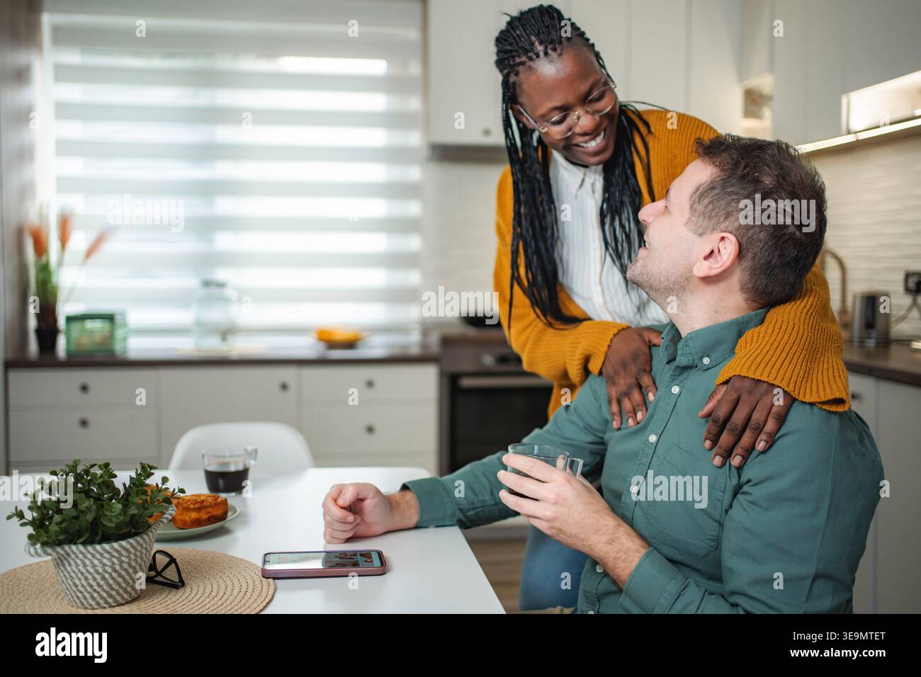 Interracial couple sharing happy morning moments in kitchen Stock Photo