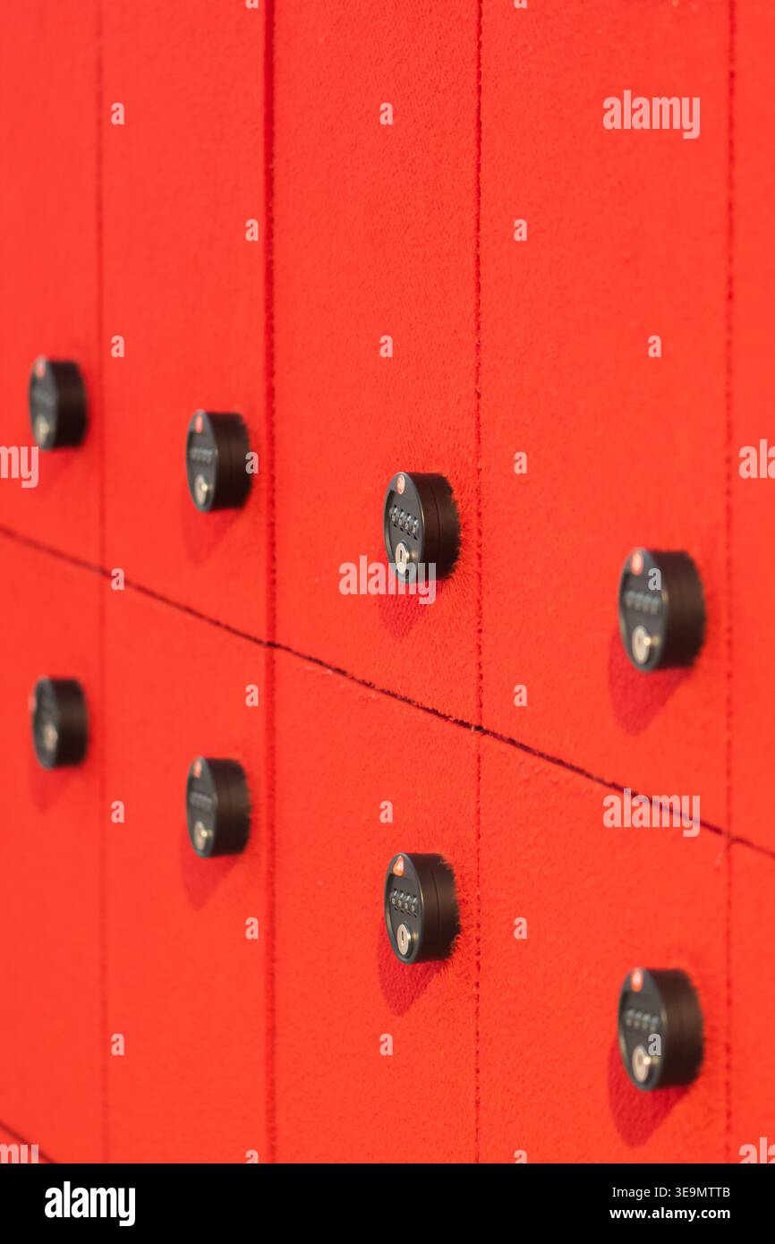 Storage lockers with code locks placed on bright red wall in modern interior. Stock Photo