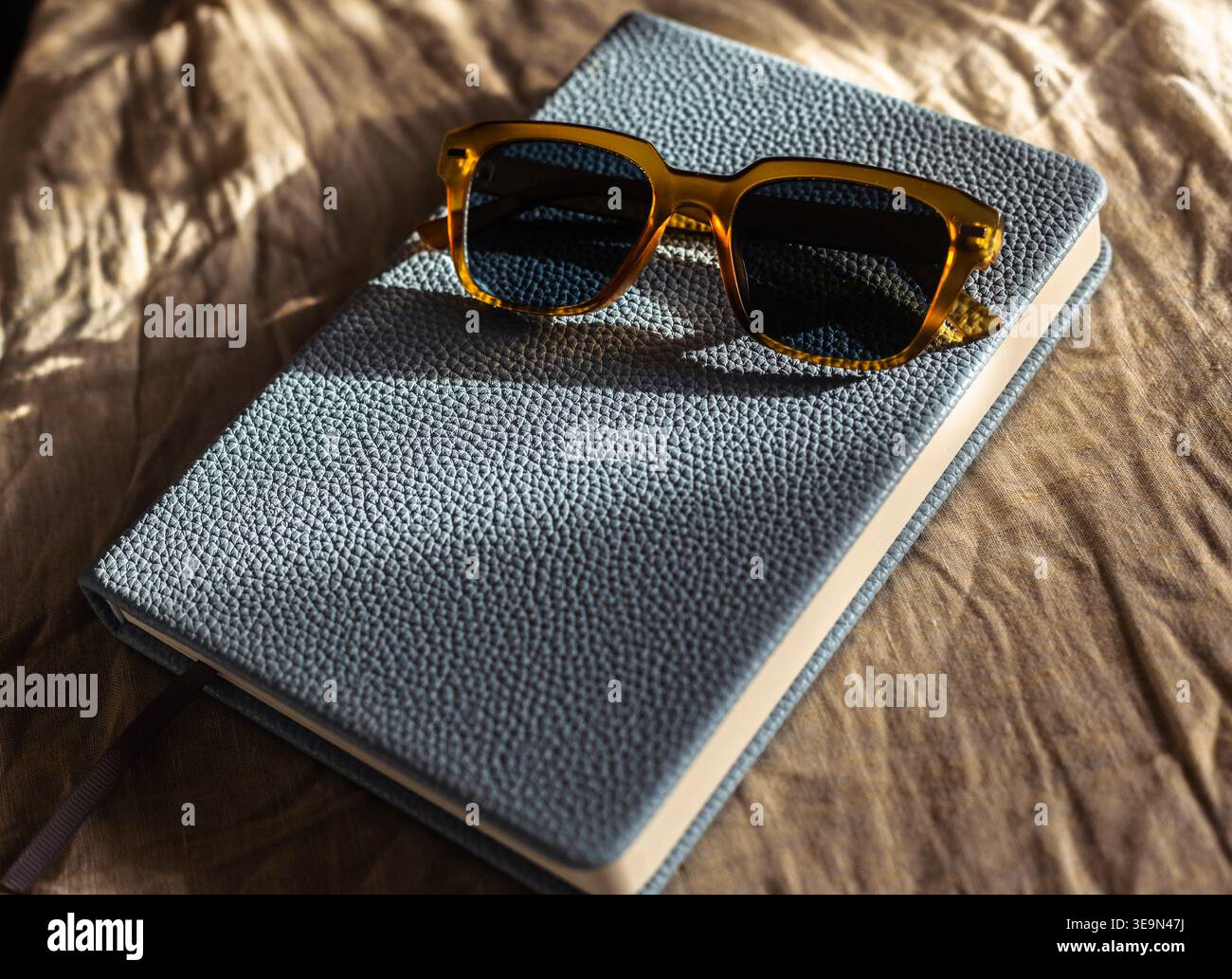 A pair of sunglasses sitting on a notebook. Stock Photo