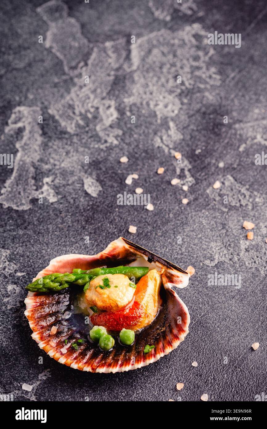 Cooked scallops with vegetables on a dark background Stock Photo