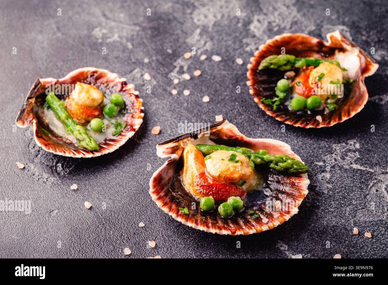 Cooked scallops with vegetables on a dark background Stock Photo