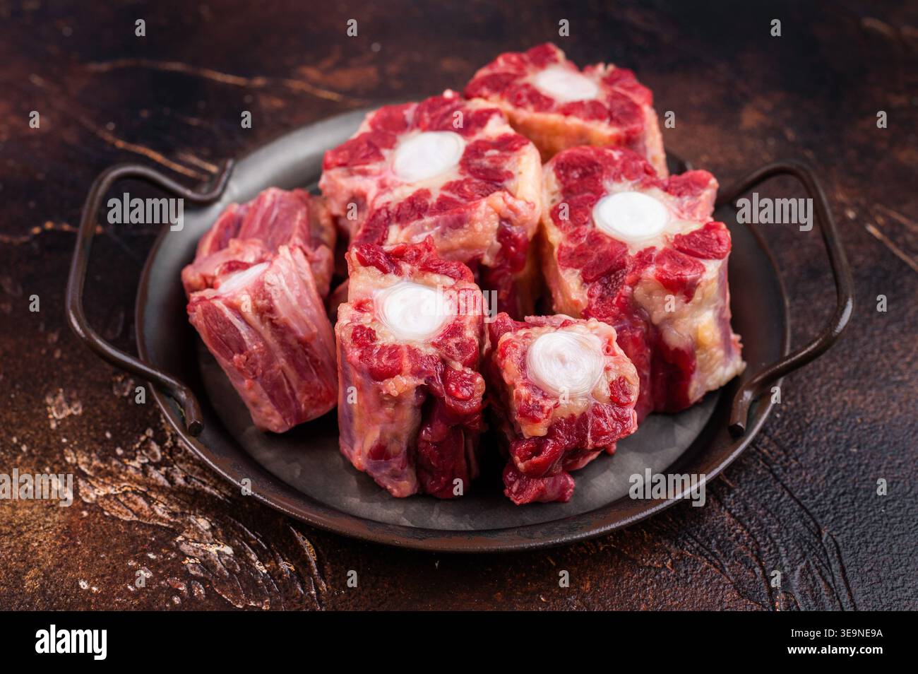 Raw Oxtail pieces in pan with fresh thyme, top view rustic food scene showing collagen rich beef for stock. Stock Photo