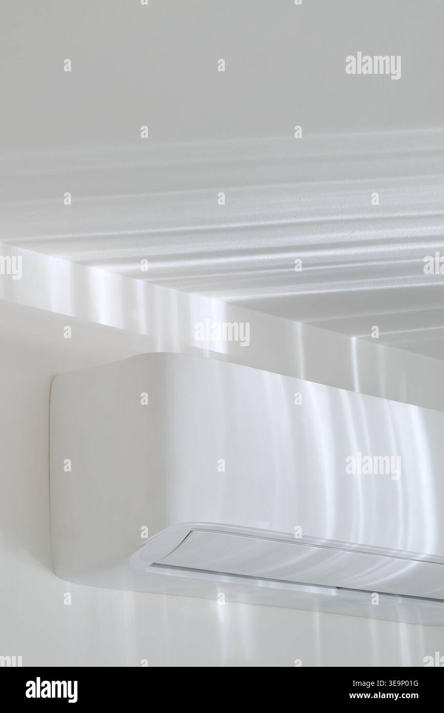 AC unit on white wall with sunlight reflections, minimal interior background, soft caustic light Stock Photo