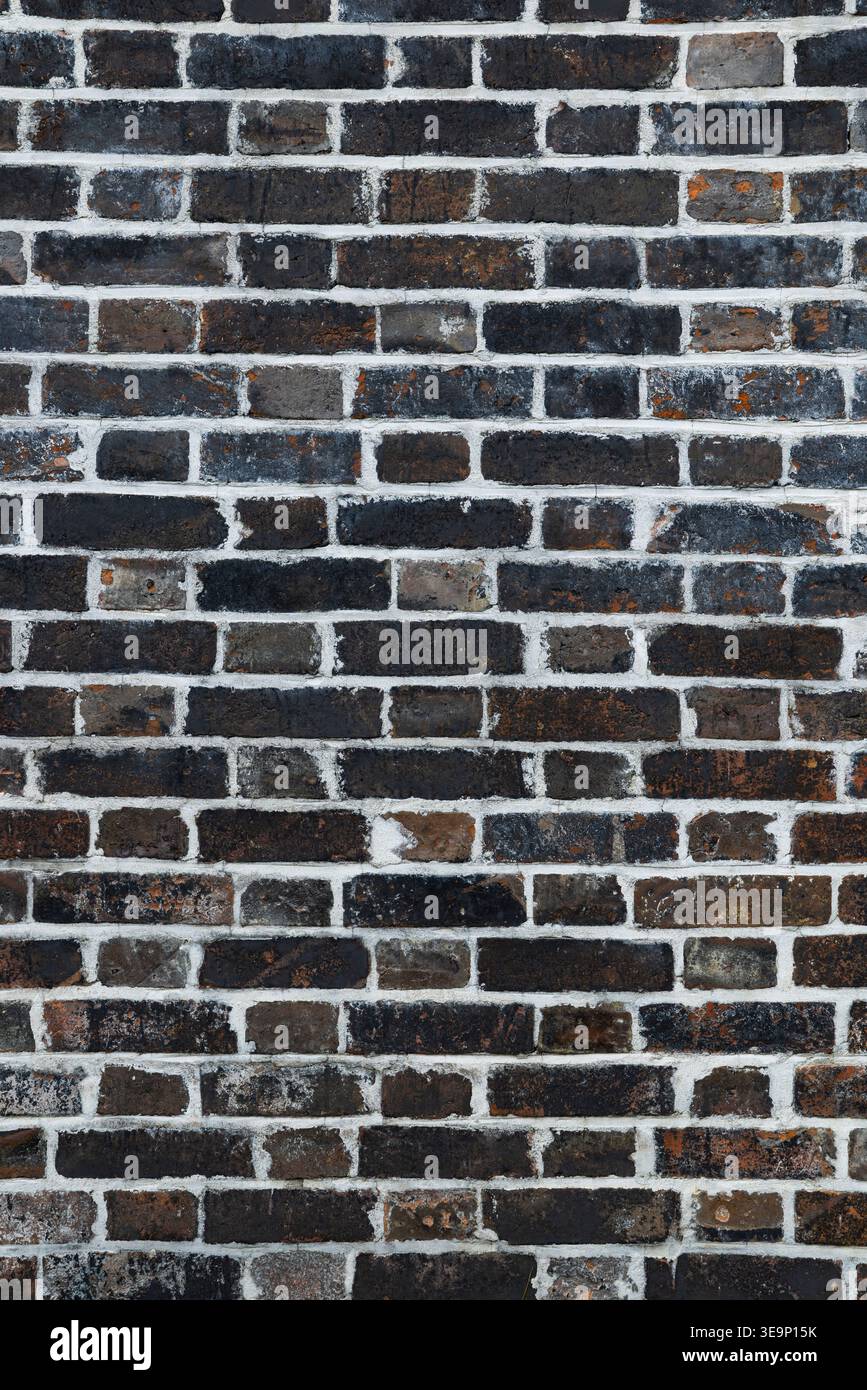 Dark brick wall with white mortar creating an abstract background surface Stock Photo