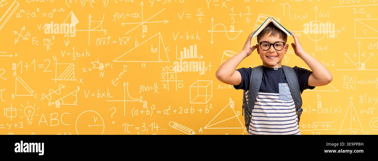 Child Holds Book Over Head and Smiles in Classroom Setting With Math ...
