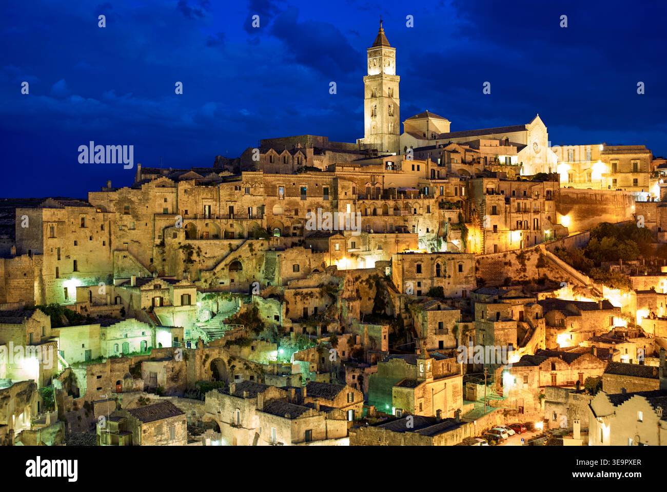 Matera shows its historic buildings and narrow streets at night. Lights shine from windows and streets, bringing life to the ancient stones. Stock Photo