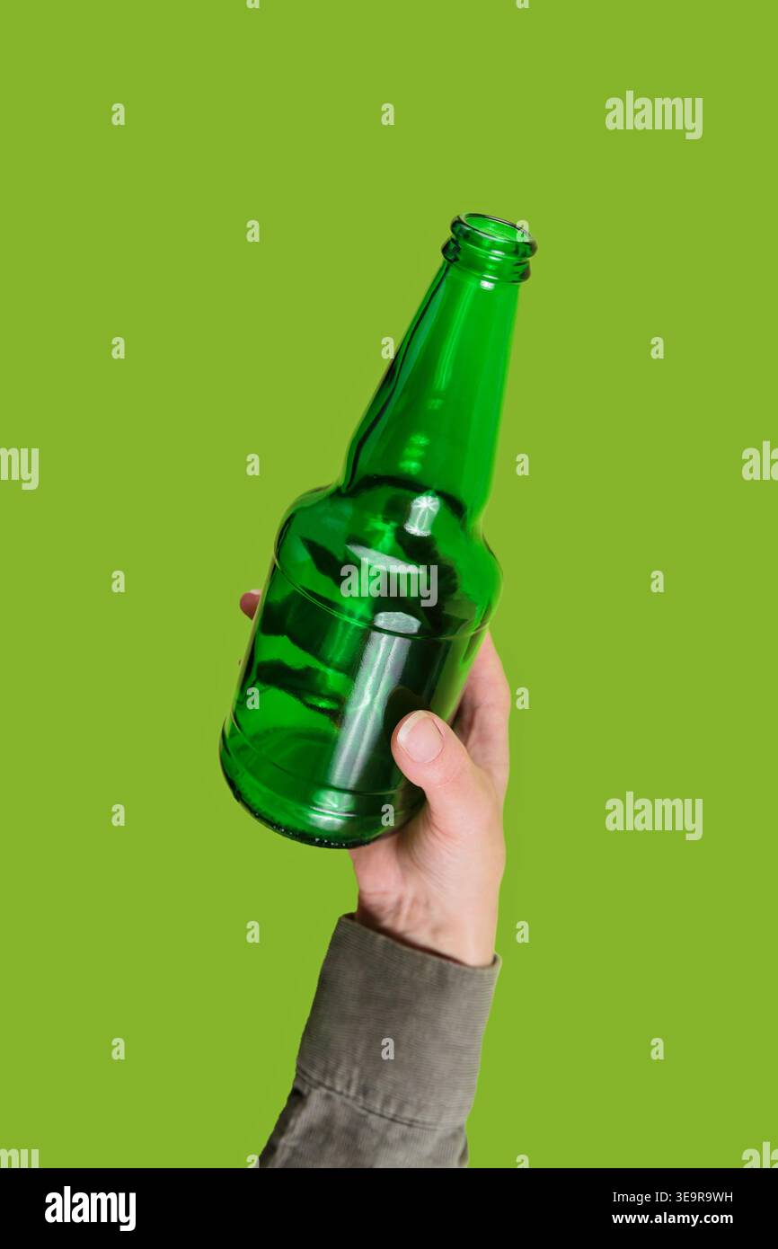 Hand holding green glass bottle on eco background Stock Photo