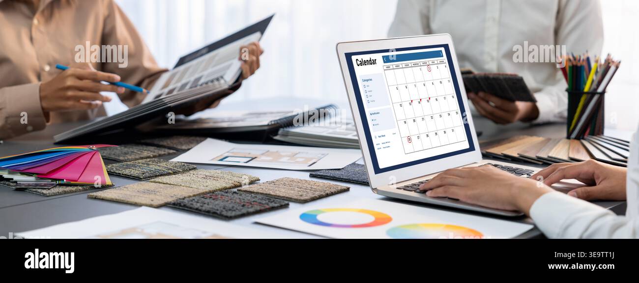 Group of interior architect designer team at table choosing color samples with architecture software on laptop screen. Modern house renovation and Stock Photo