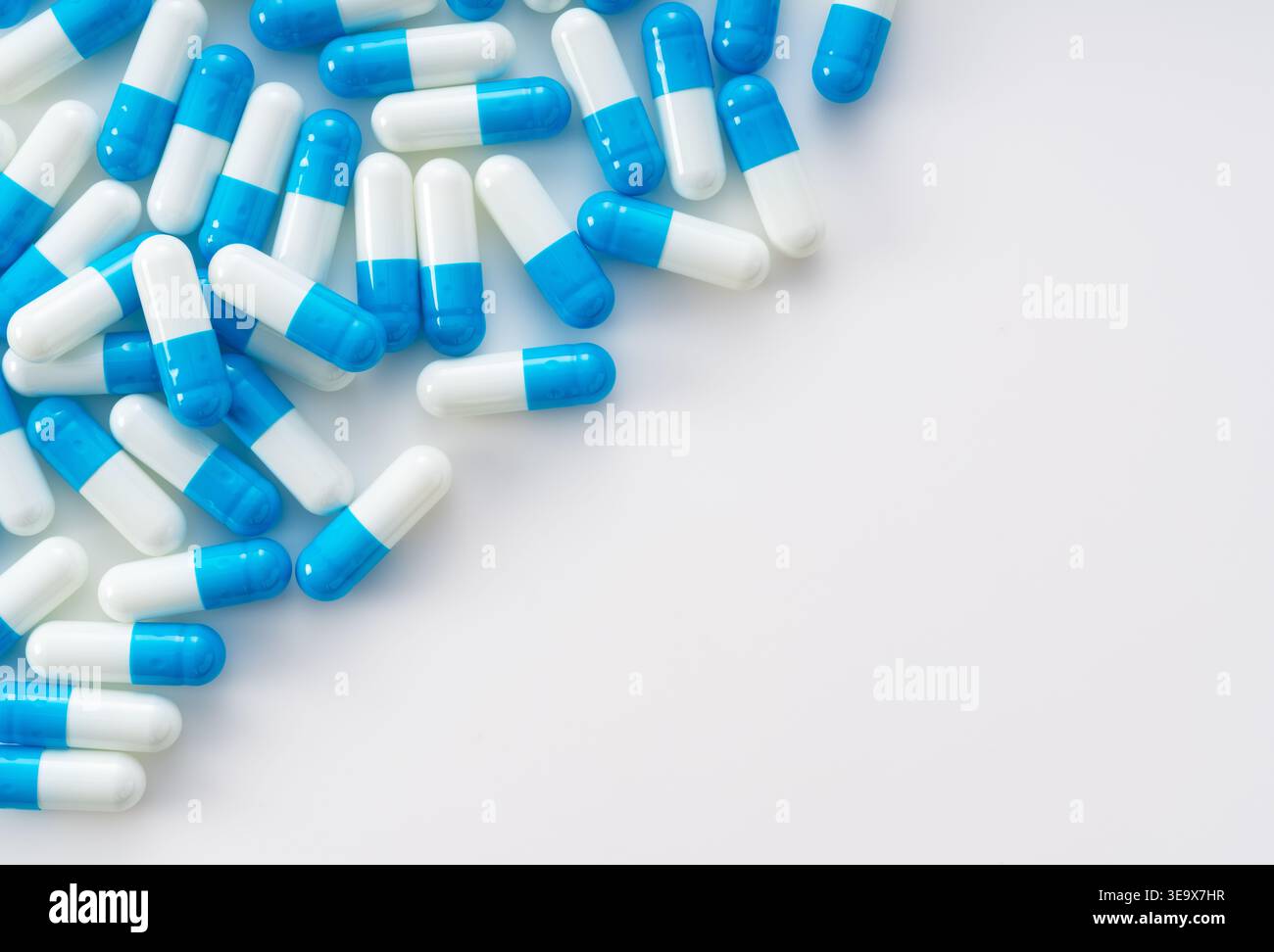 Blue and white capsules on white background with copy space, medical and healthcare concept flat lay Stock Photo
