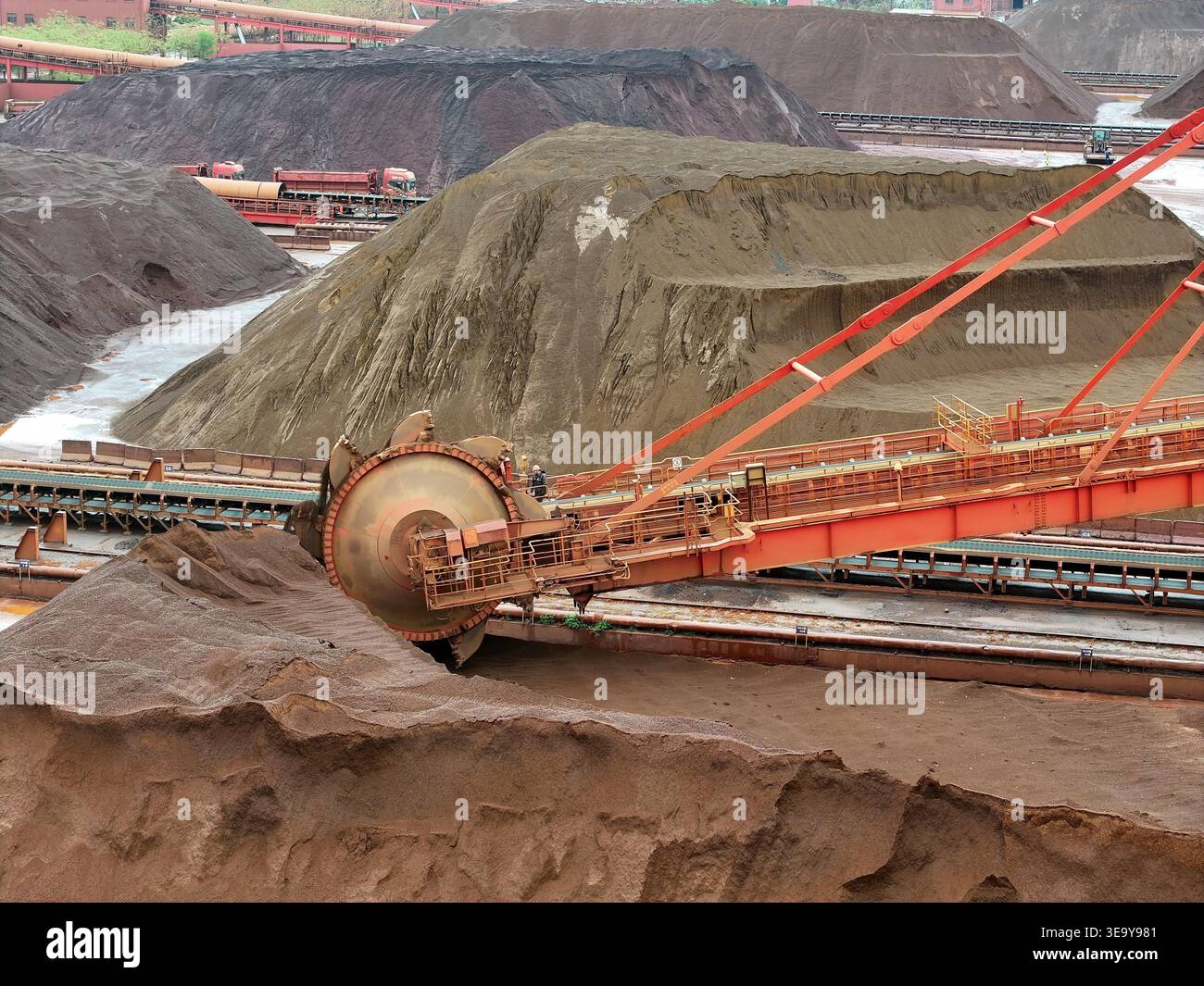 Large machinery stacks imported iron ore unloaded from cargo ships at ...