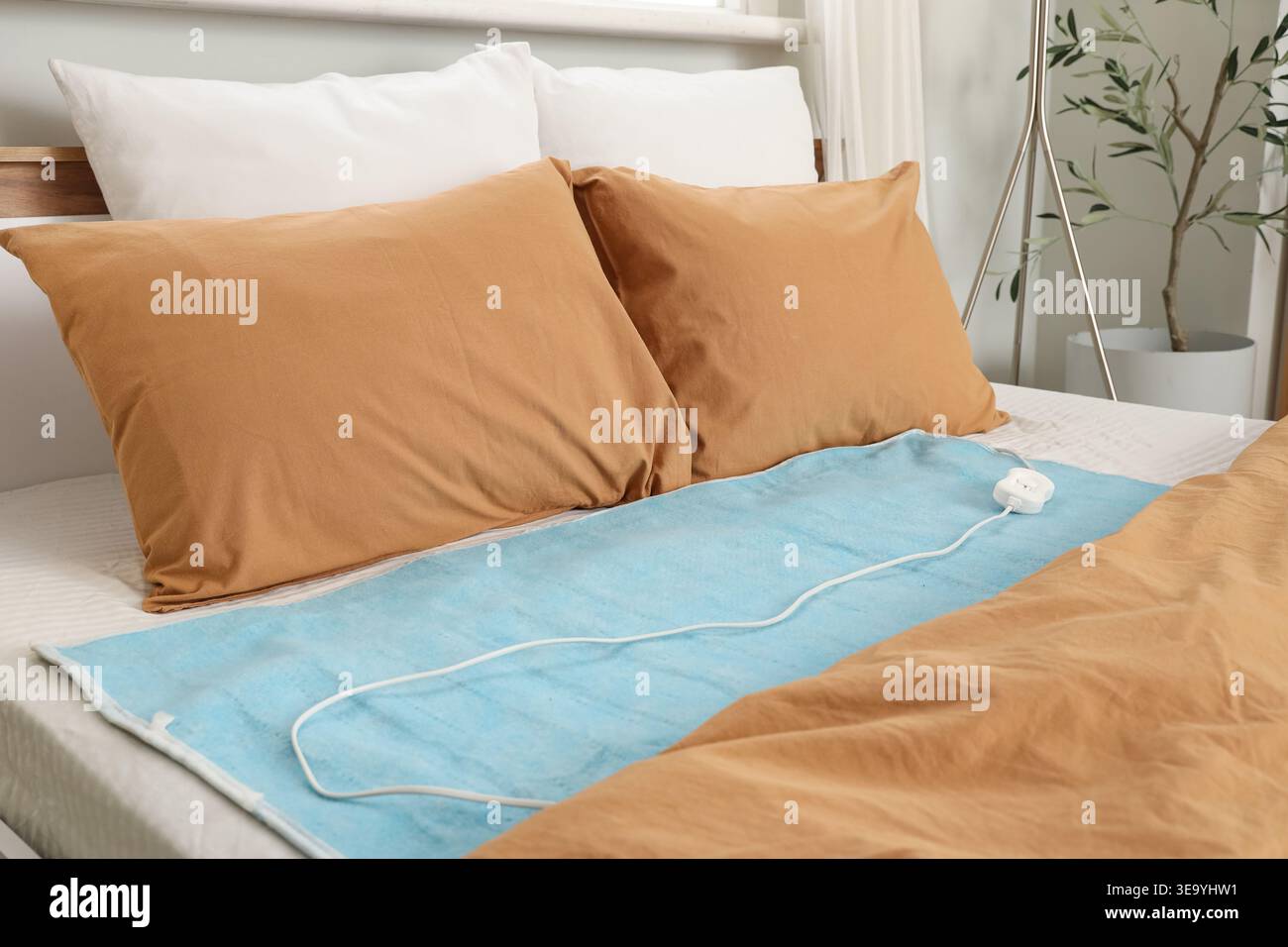 Electric heating pad on bed in room Stock Photo