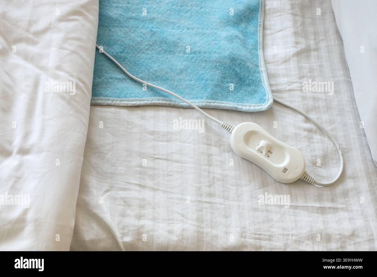 Modern electric heating pad on bed, top view Stock Photo