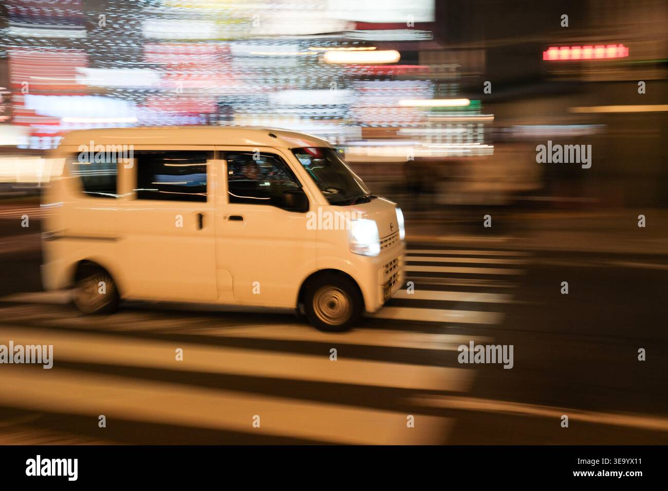 White delivery van speeds through a city at night with motion blur ...
