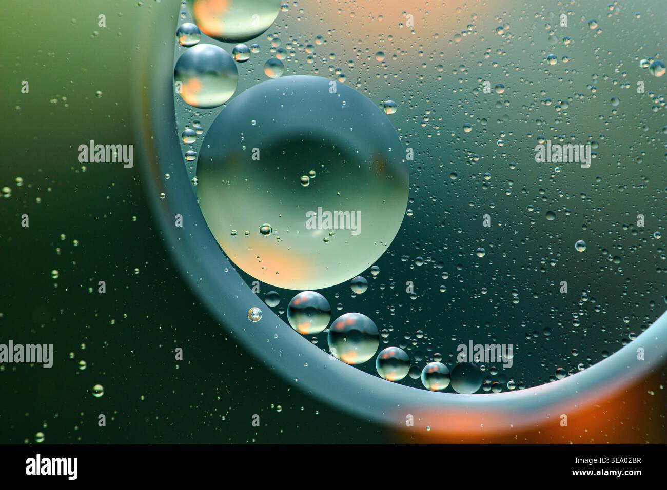 Oil droplets suspended in water creating an abstract pattern with reflections and refractions, highlighting immiscibility and surface tension. Photogr Stock Photo