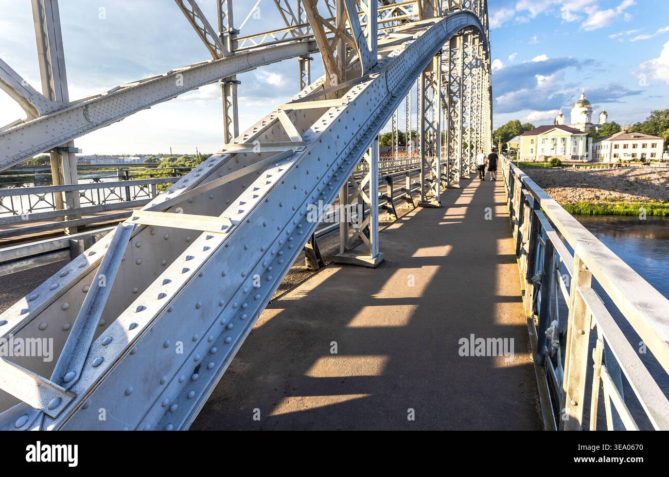 View on the steel arch bridge across the Msta river in summer day in sunset light. Built in 1905. Borovichi, Russia Stock Photo