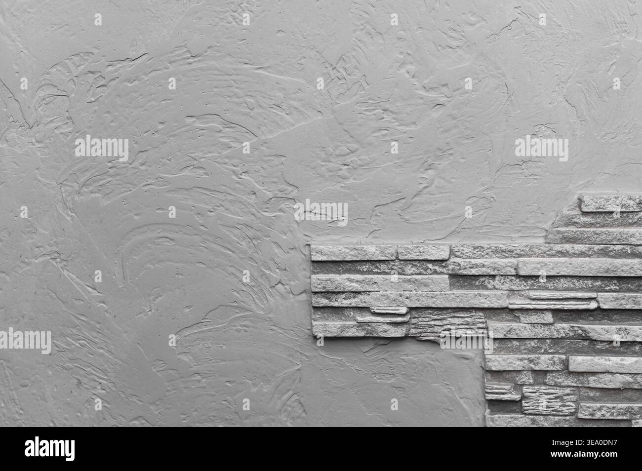 Textured gray wall with stone cladding on one side, creating modern and minimalistic design. creative concrete backdrop. rough stone pattern, adding v Stock Photo