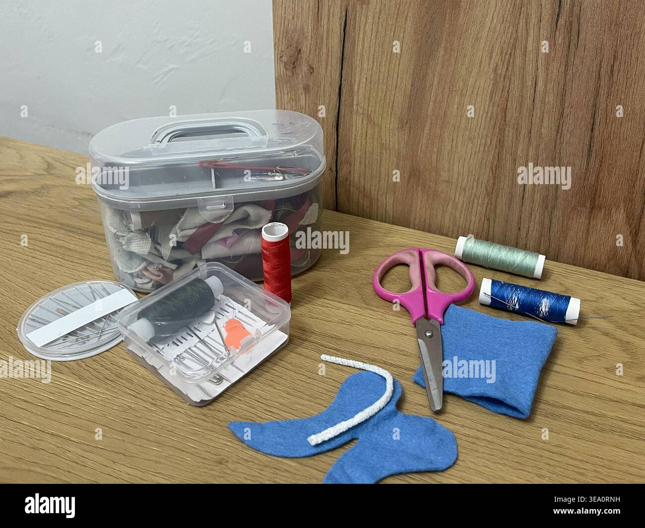 A tailor's sewing kit on a table. Needles, thread, and fabric for sewing. Stock Photo