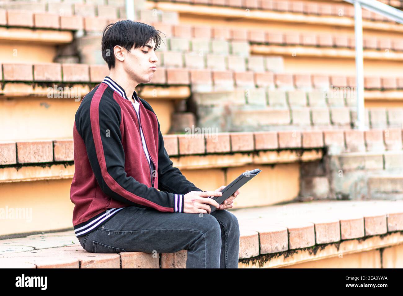 Young student analyzing information on digital tablet outdoors Stock Photo