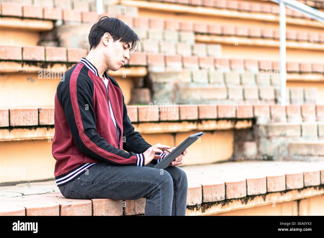Young man studying outdoors using digital tablet Stock Photo