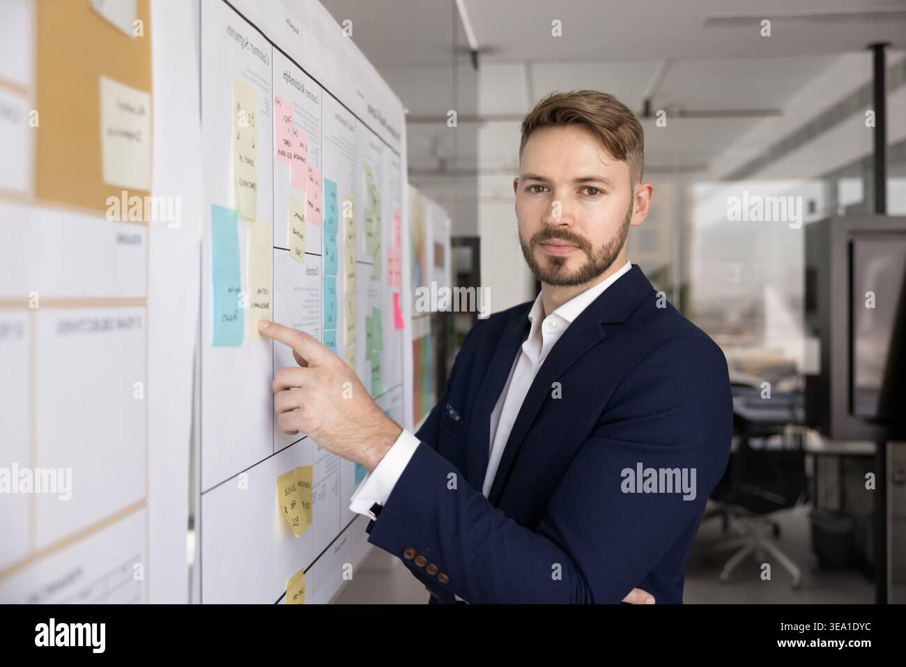 Businessman pointing to sticky note while looks at camera Stock Photo