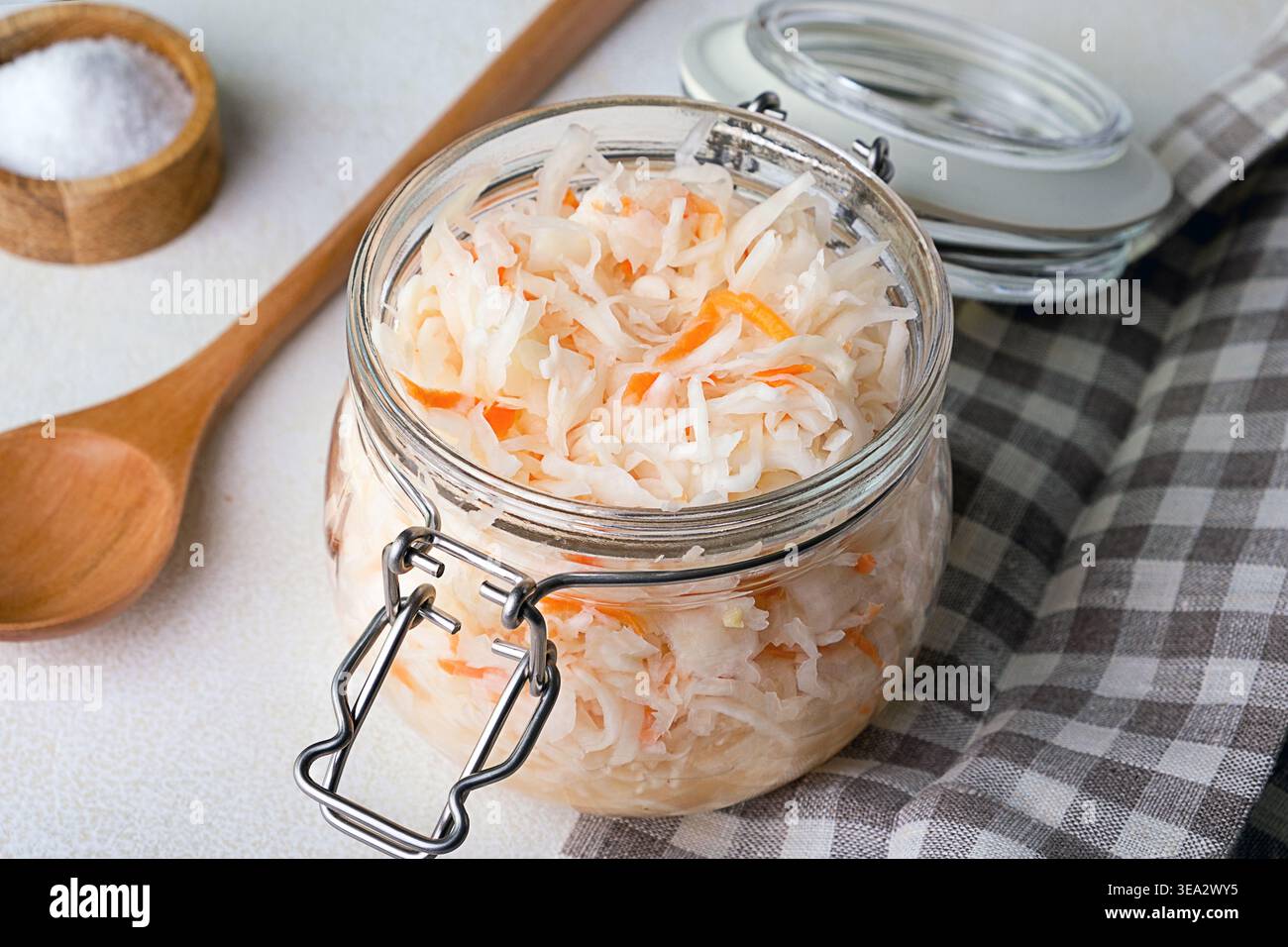 Close-up of sauerkraut in a glass jar. Traditional fermented food displayed on wooden board. Stock Photo