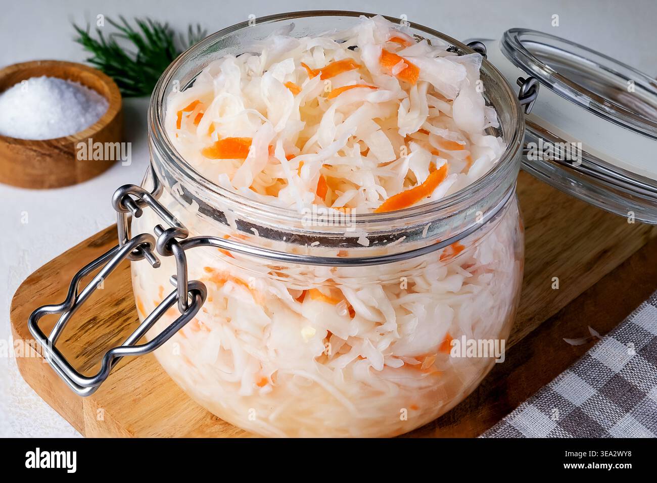 Close-up of sauerkraut in a glass jar. Traditional fermented food displayed on wooden board. Stock Photo