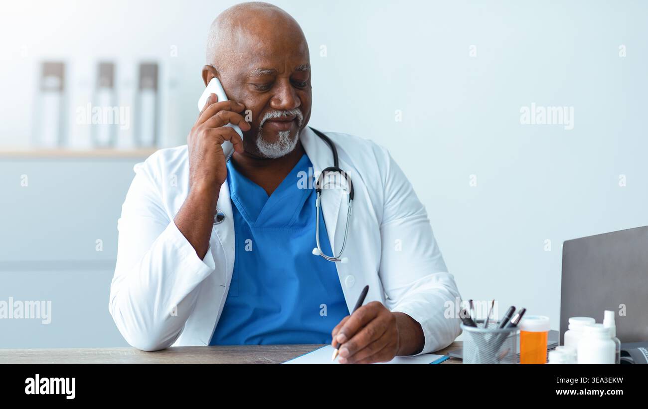 Doctor on the Phone While Taking Notes in a Medical Office Stock Photo