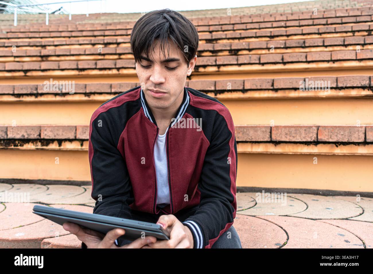 Young man sitting on steps using digital tablet Stock Photo