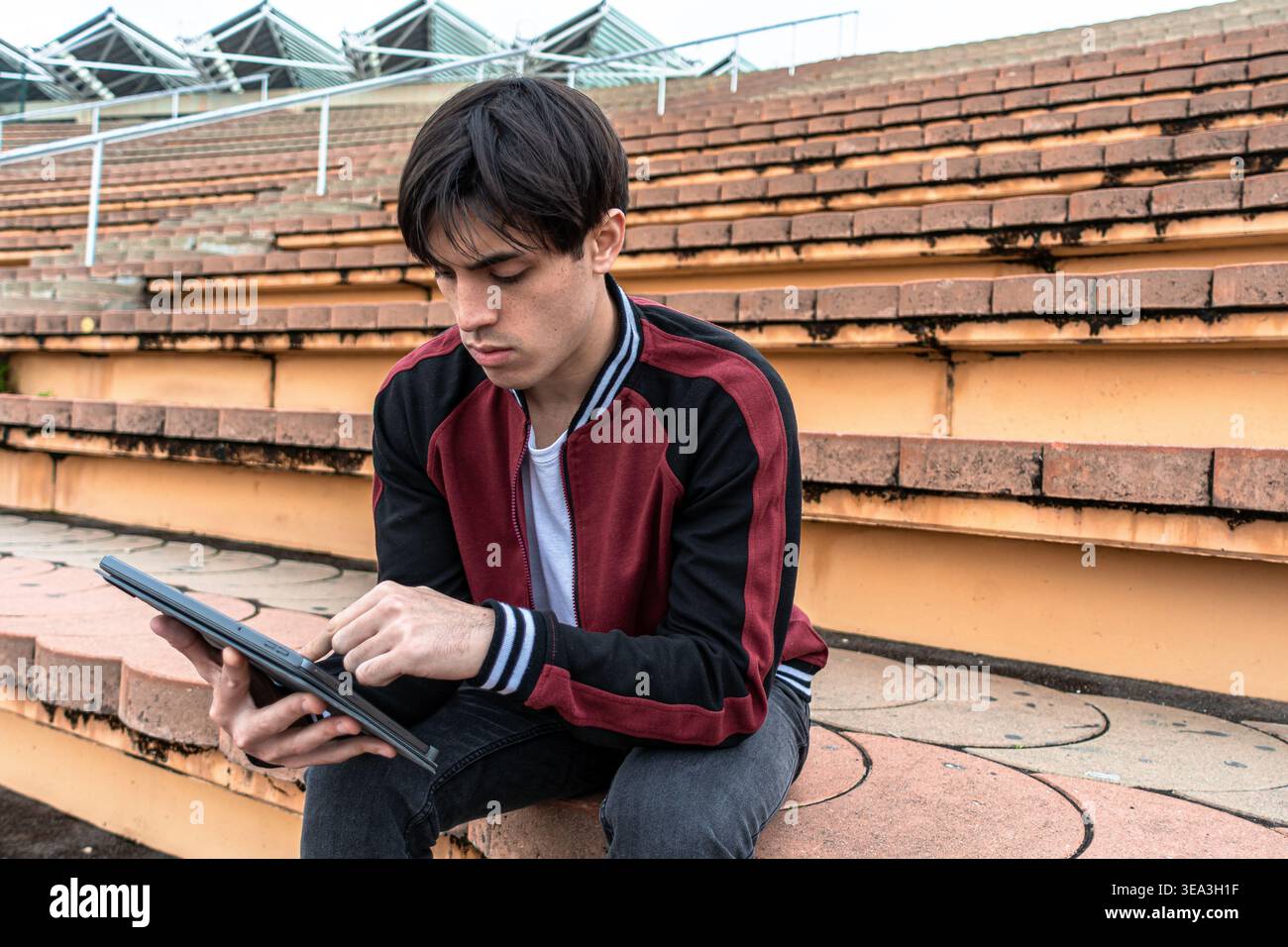 Young man using digital tablet on stadium steps Stock Photo