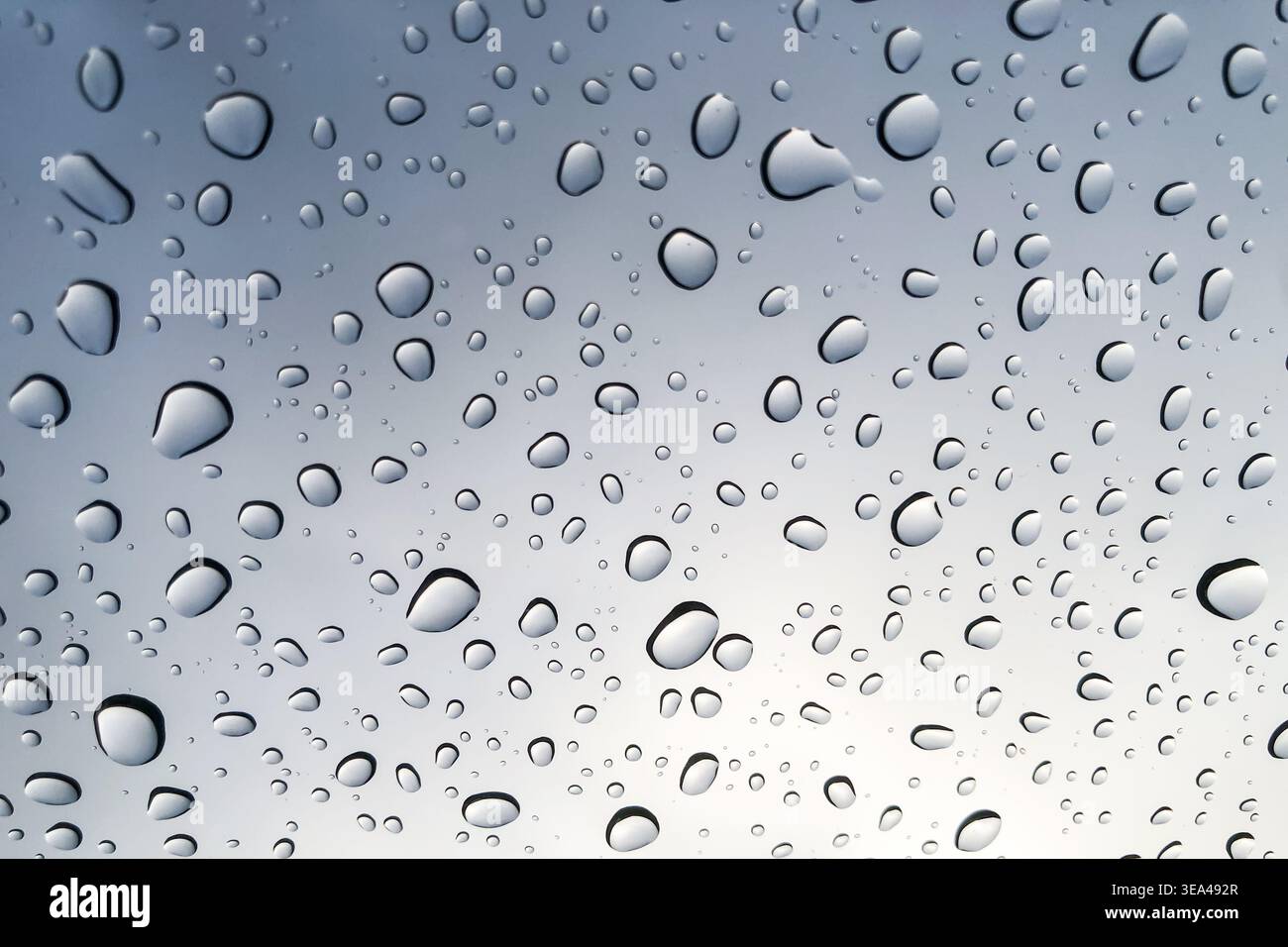 Raindrops on the glass look up to the sky blurred in the background. Stock Photo