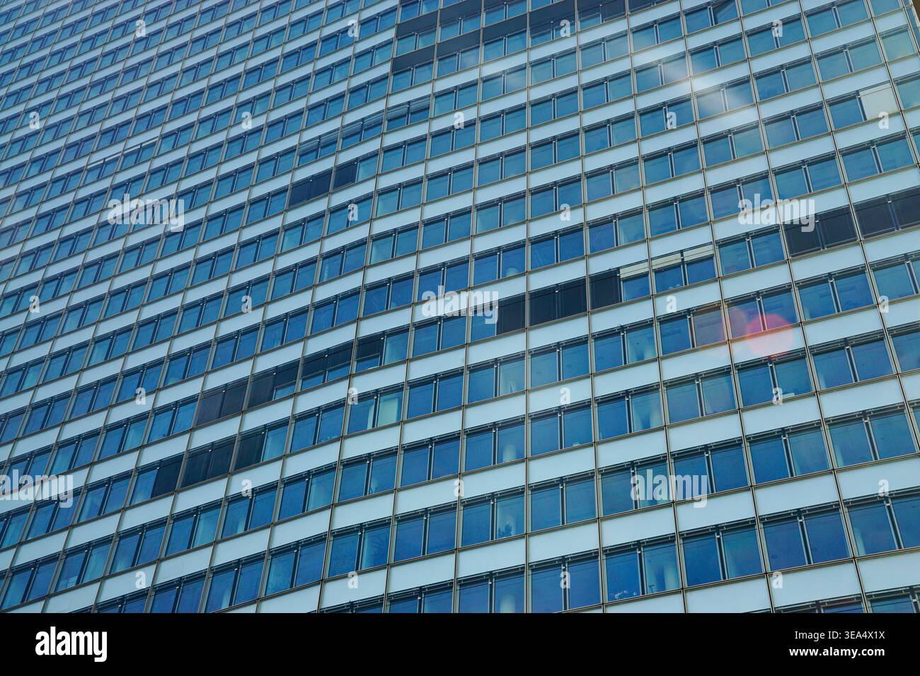 Modern office building facade with repetitive glass windows and metal grid structure viewed in daylight in Vienna, showing geometric pattern and refle Stock Photo