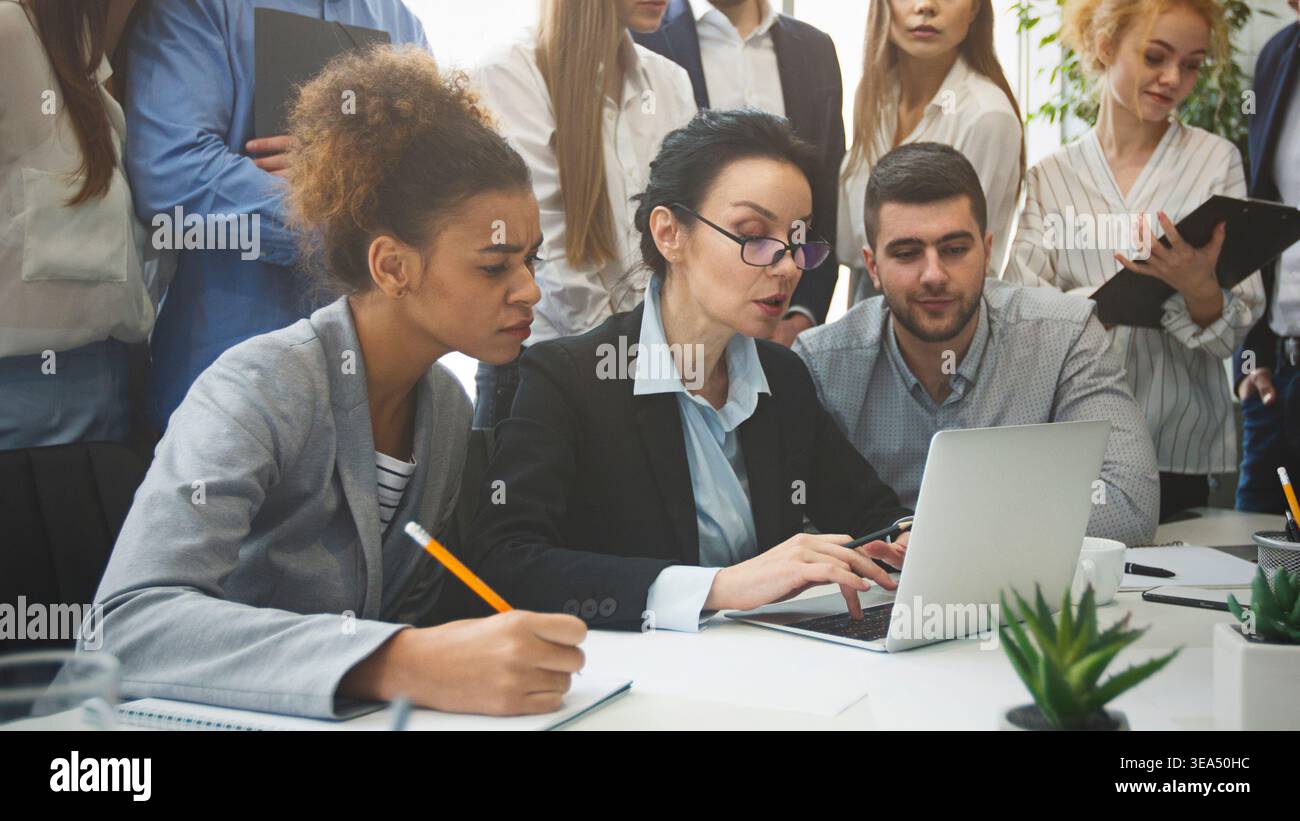 Serious business team analyzing reports on laptop Stock Photo