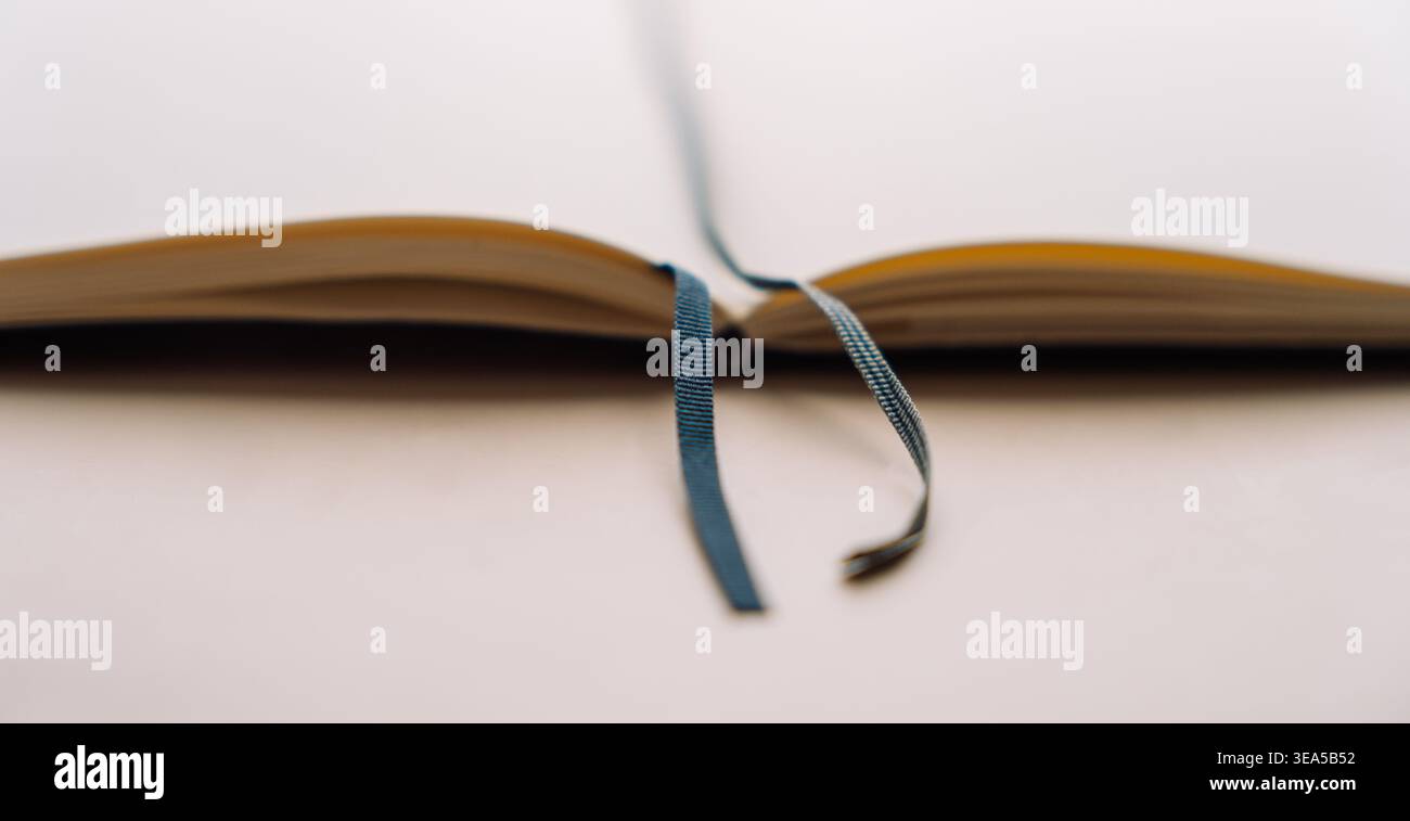 Open dot grid notebook with ribbon bookmark on beige background Stock Photo