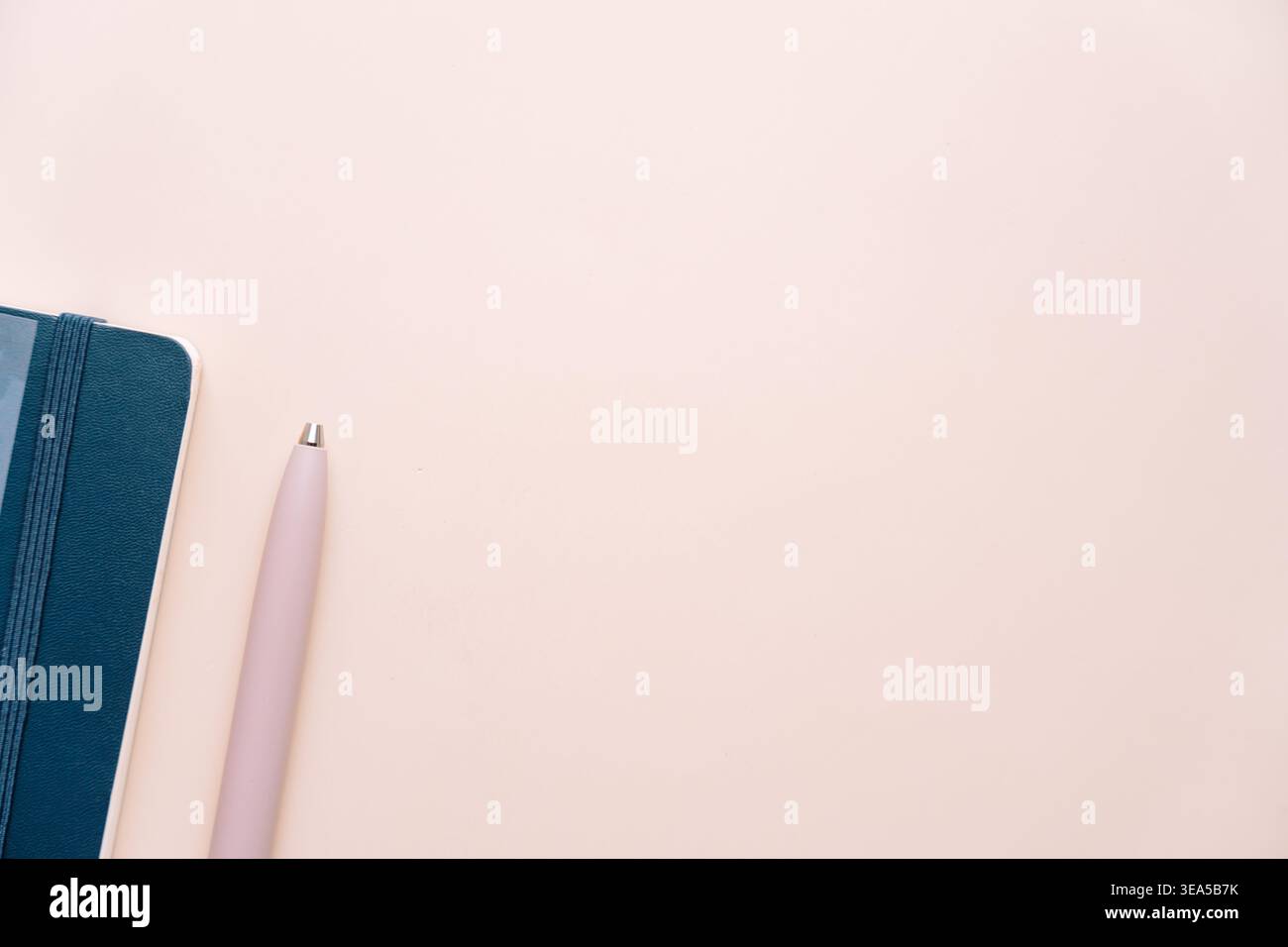 Blue notebook and pink pen on soft beige background Stock Photo