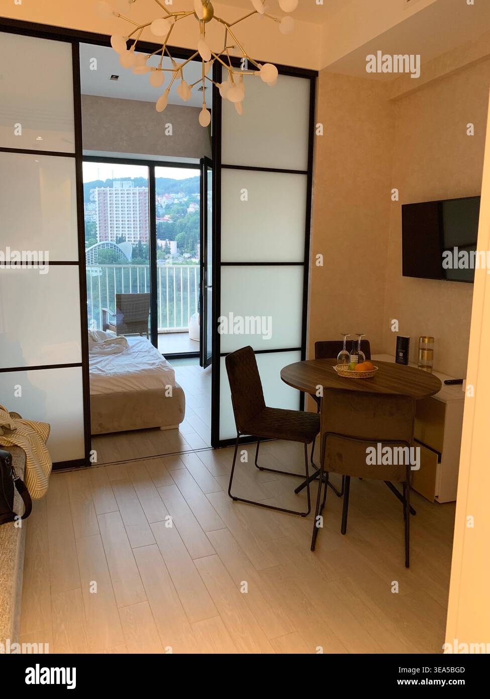 Modern cozy apartment interior with dining area, bedroom and balcony view, minimalistic design with warm lighting - Smartphone Captured Stock Image