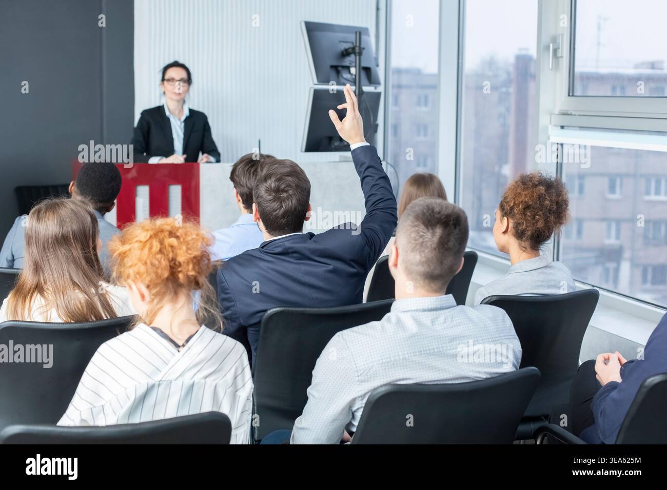 Businessman raising hand at seminar, having question to speaker Stock Photo