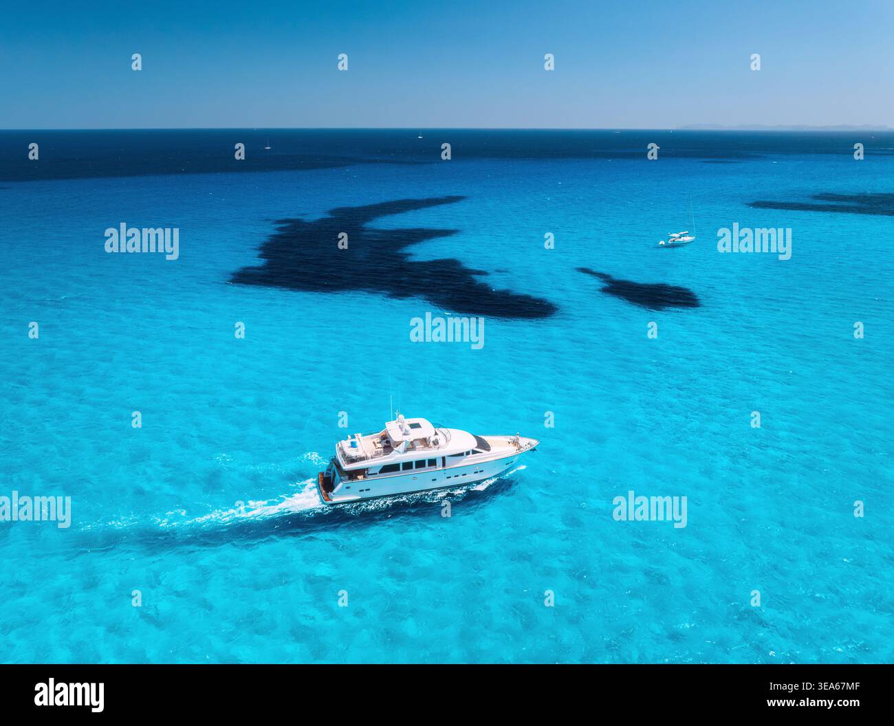 Aerial drone view of luxury yacht moving through shallow turquoise sea ...