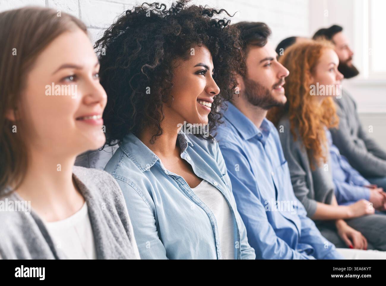 Diverse millennial group sitting in row, waiting for something Stock Photo