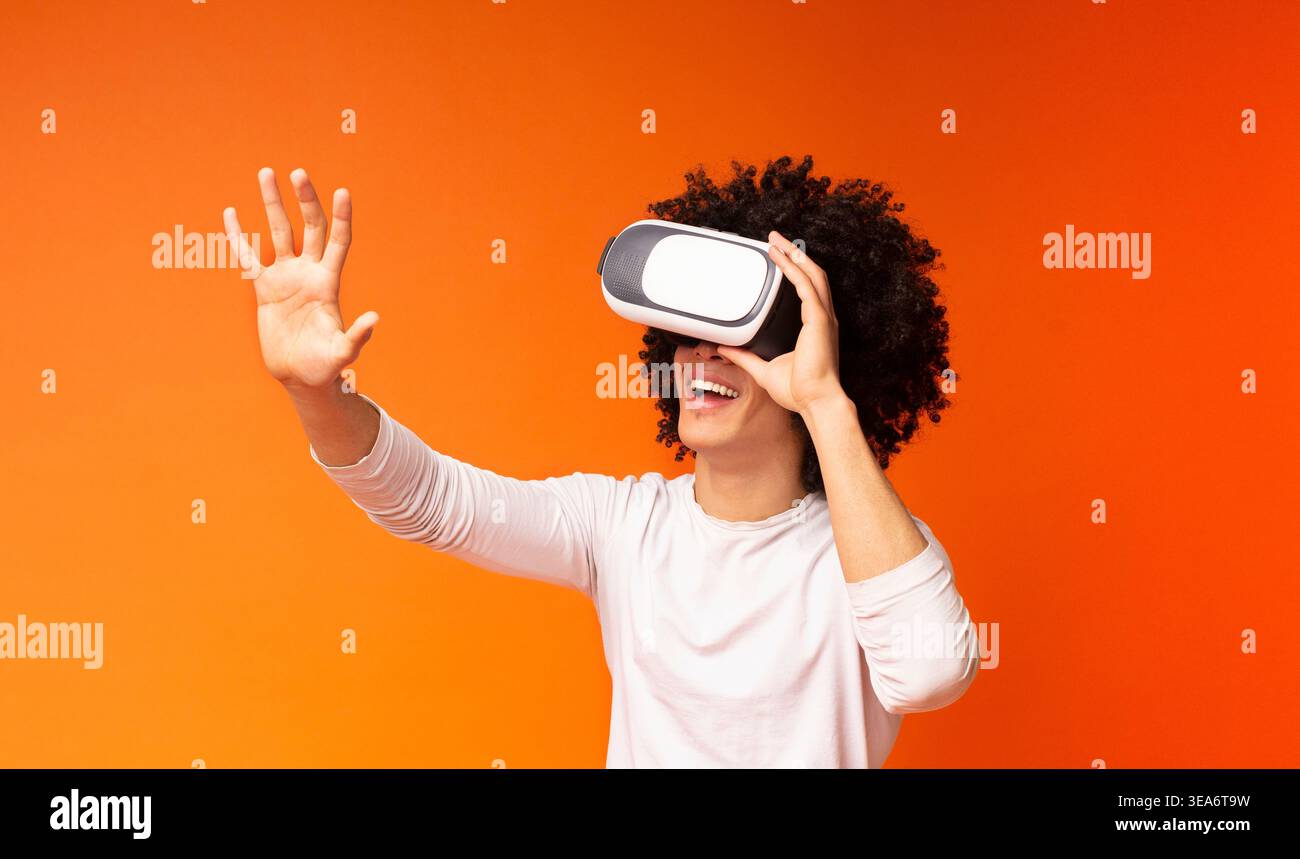 Excited black guy pushing virtual button in VR glasses Stock Photo