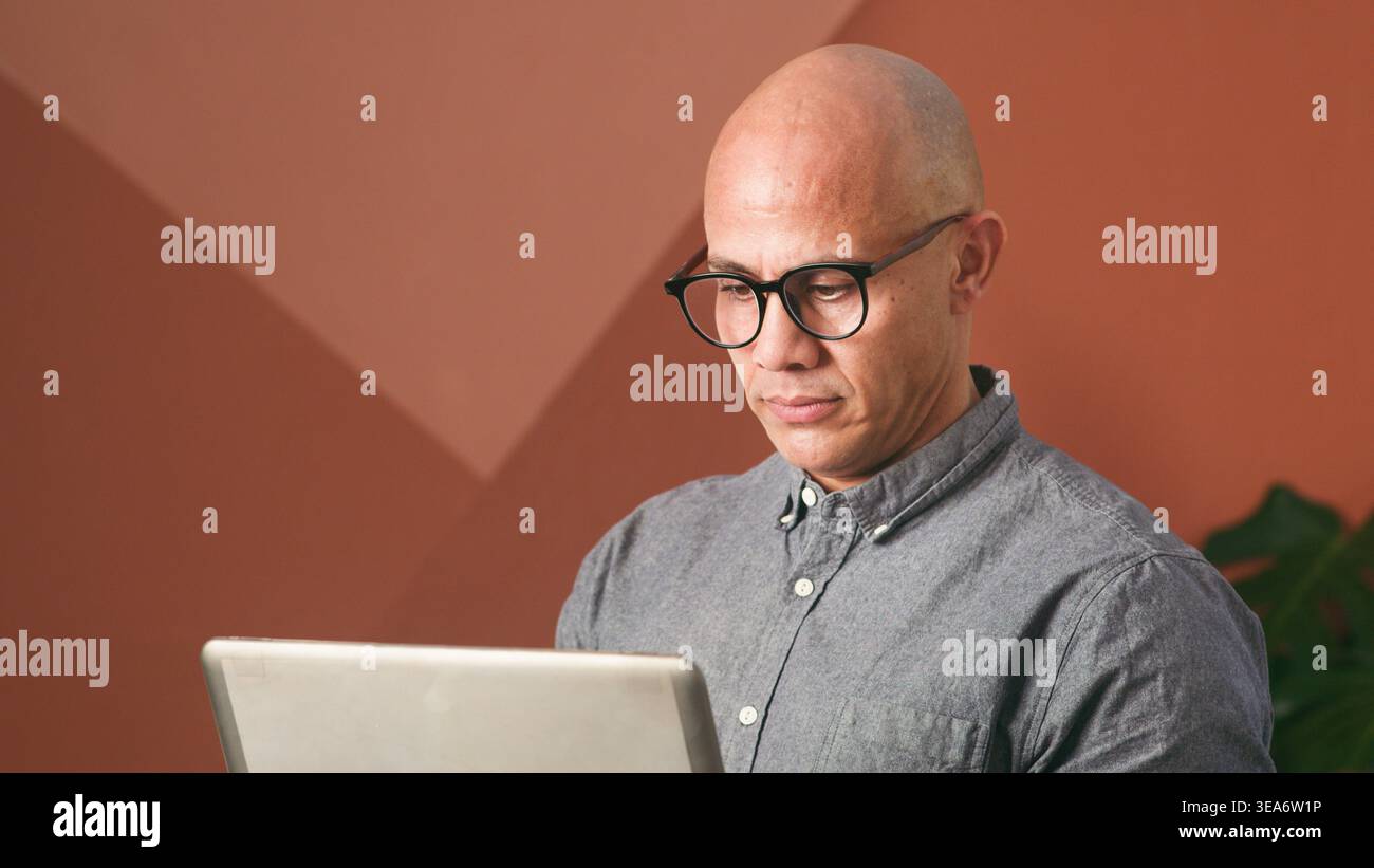 Businessman Working On Laptop In Modern Office With Glasses Concentrating On Screen Stock Photo