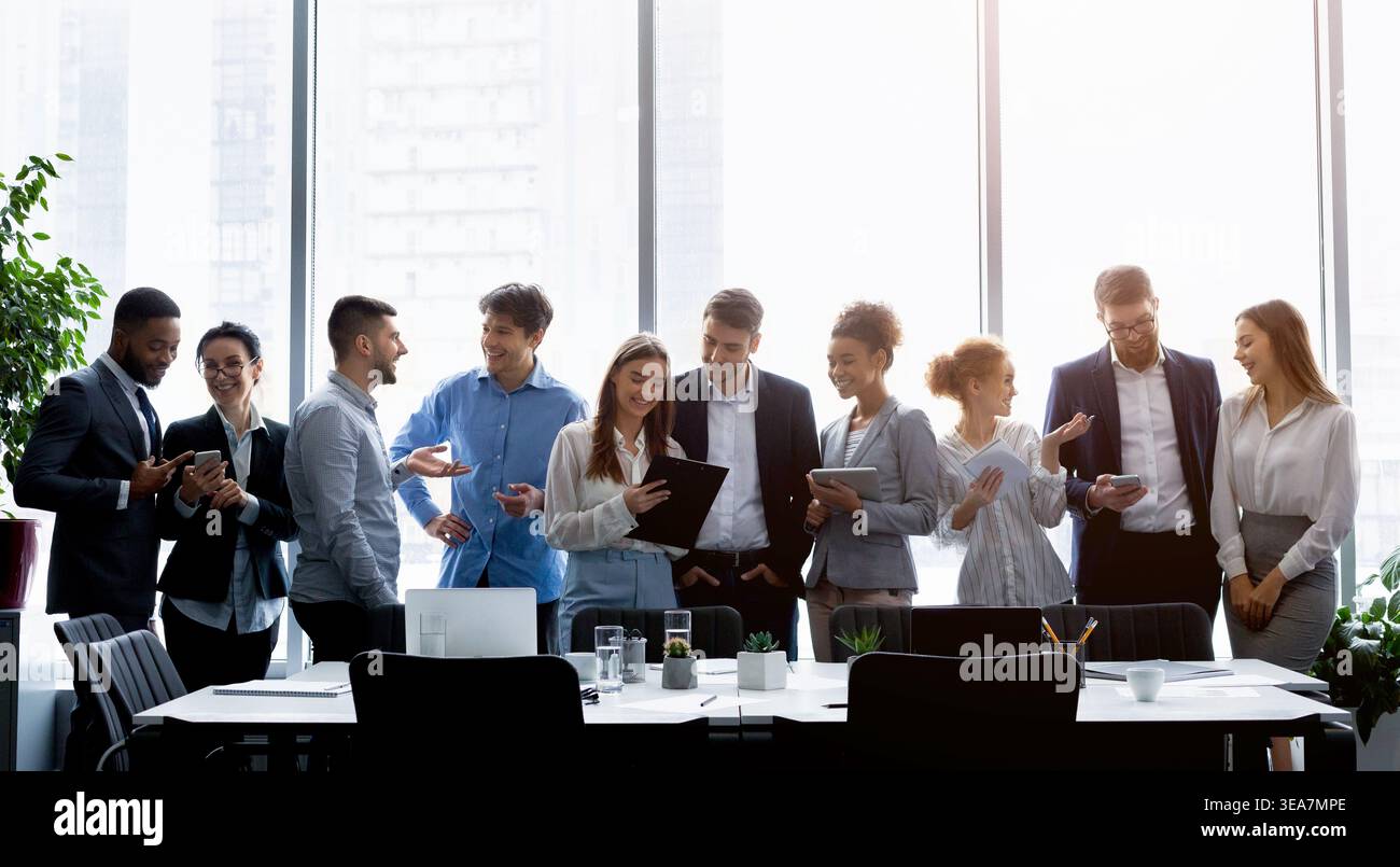 Business people standing against window, discussing work Stock Photo