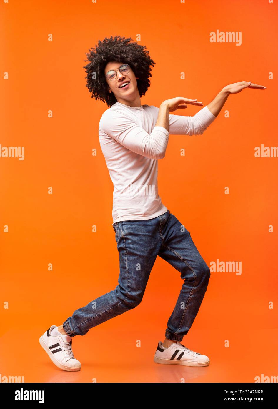Funny black guy dancing in egypt style on orange background Stock Photo
