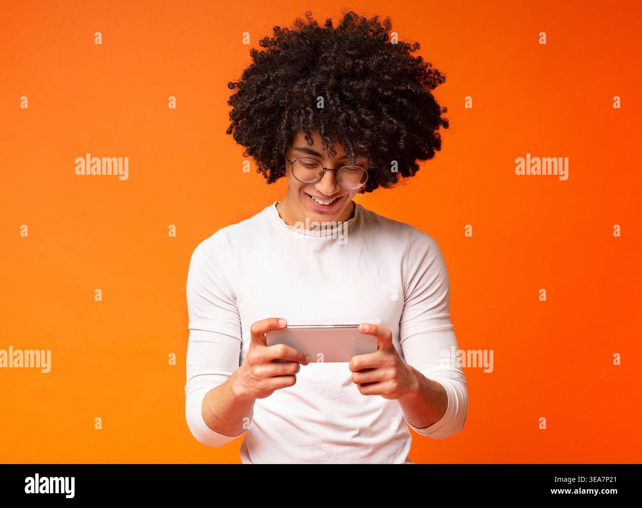 Cheerful young man watching video on cellphone Stock Photo
