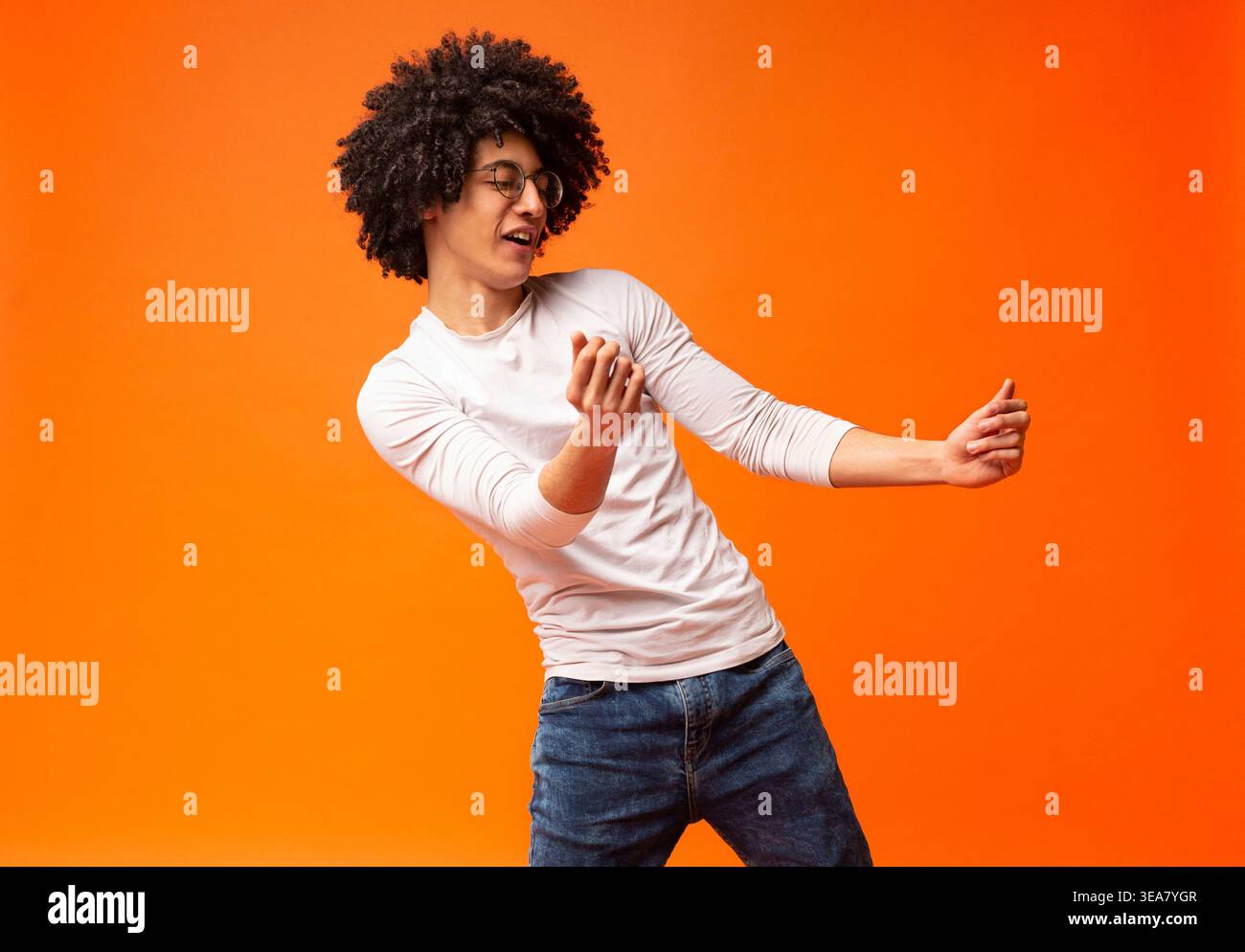 Flexible millennial black guy dancing on orange background Stock Photo