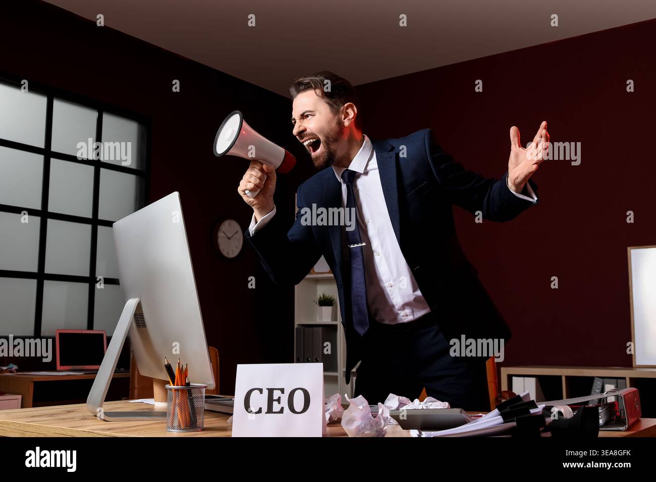 Angry businessman shouting into megaphone in office Stock Photo