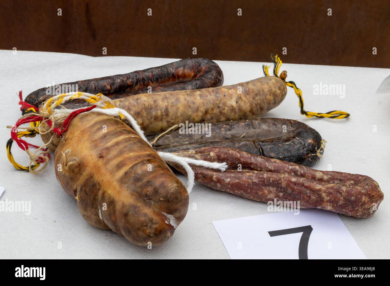 Assorted cured sausages on white surface with rustic presentation Stock Photo