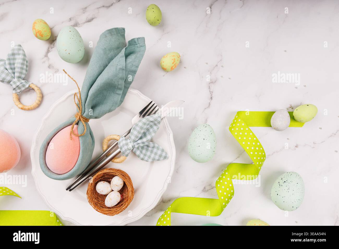 Pastel Easter Setting with Eggs, Napkin Bunny and Ribbon Stock Photo