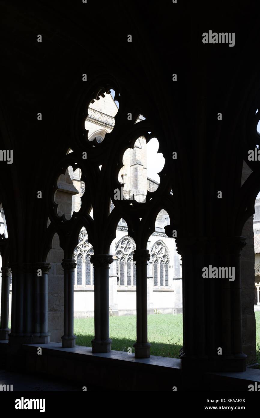 Dark corridor with gothic arches framing bright courtyard creating ...