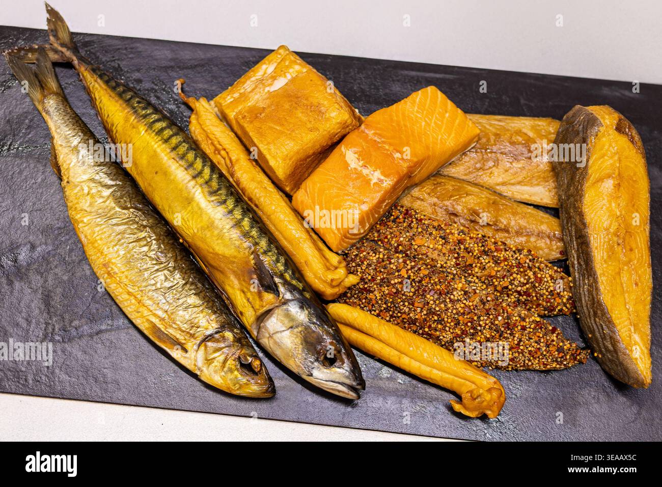 Different types of fish and seafood are arranged on a black platter ...