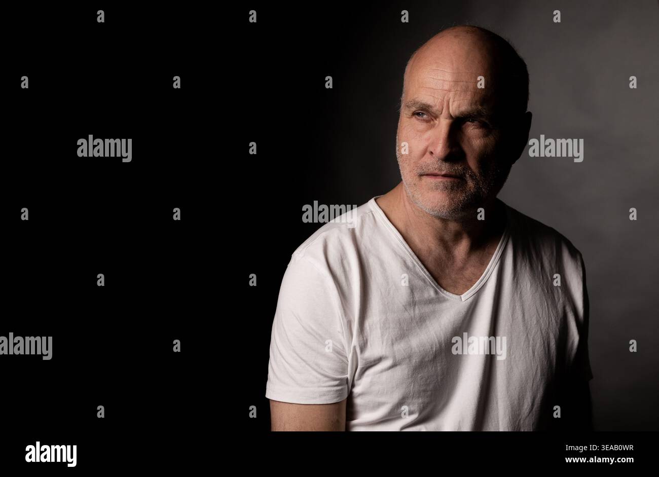 Bald man contemplating, thinking, or remembering on a dark background Stock Photo